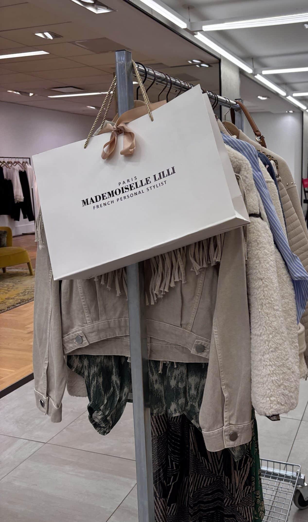 A Mademoiselle Lilli branded garment bag hanging on a clothing rack during a personal styling session